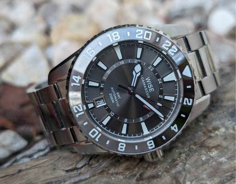WISE ADX 110 True GMT watch dial close-up showing branding, 24-hour bezel, and automatic movement details